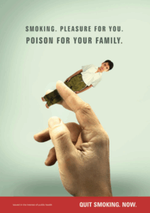 A hand holds a small boy like a cigarette. Above, text reads: Smoking. Pleasure for you. Poison for your family. A red banner at the bottom says, Quit smoking. Now.